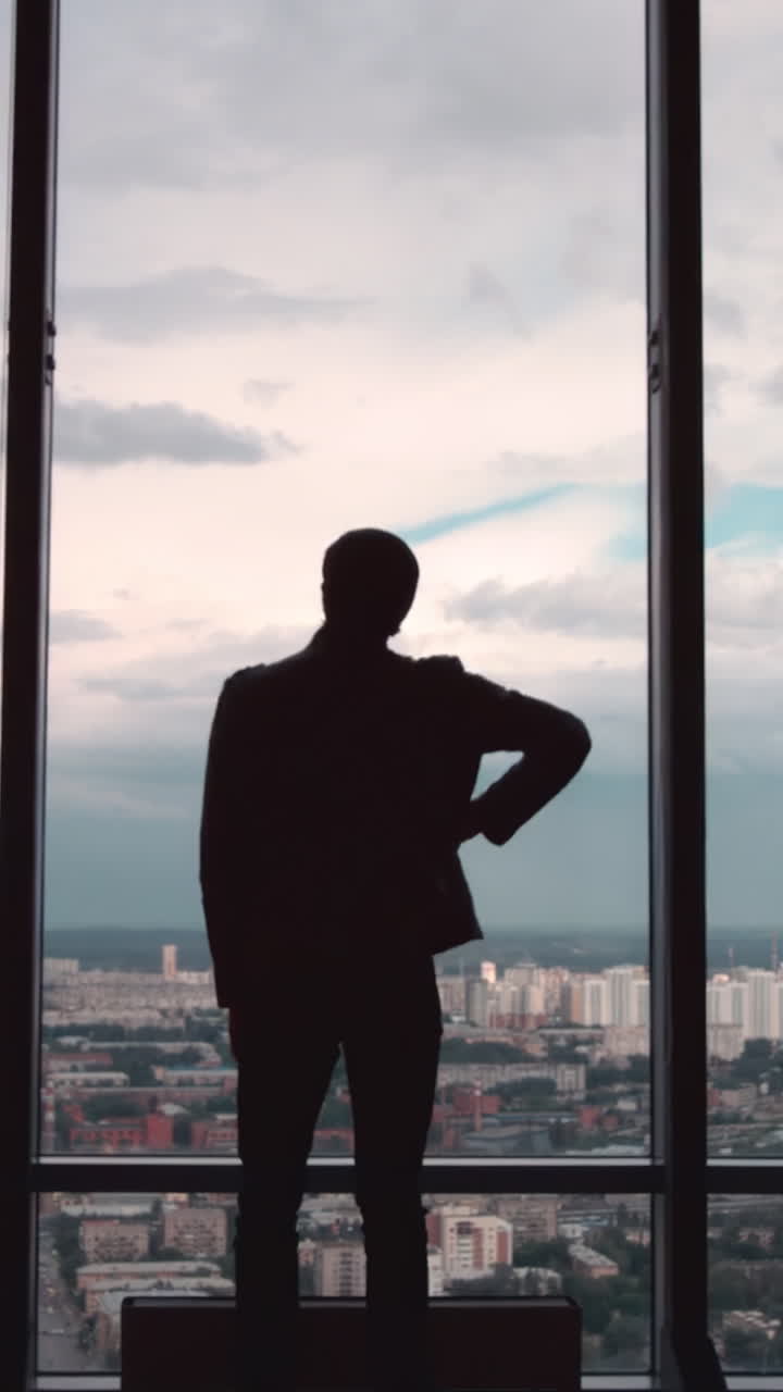 un hombre de negocios contemplando el paisaje de la ciudad desde una ventana de gran altura.