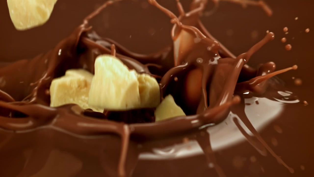 Pezzi di cioccolato bianco che si tuffano nel cioccolato al latte fuso al rallentatore
