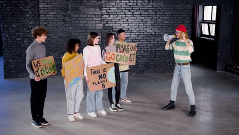 young female environmental leader with megaphone motivating her friends to protest against climate change inaction