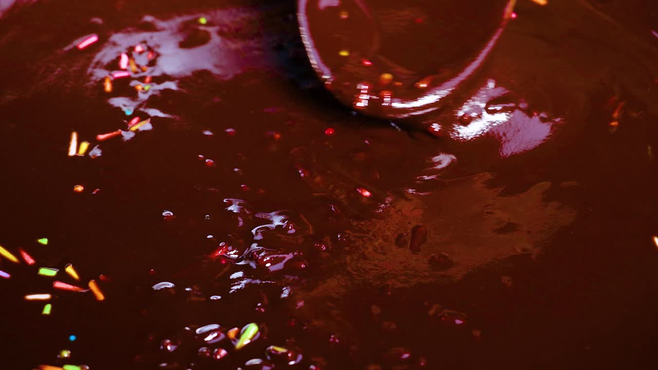 Cucchiaio che mescola cioccolato con zuccherini colorati