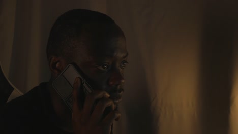 black male on a serious phone call at home office