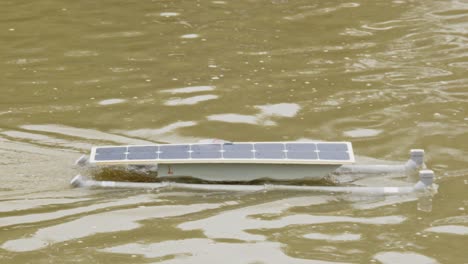 Wunderschöne-Nahaufnahme-Eines-Selbstgebauten,-Ferngesteuerten-Solarboots,-Das-Von-Einem-Photovoltaik-Solarmodul-Auf-Der-Oberseite-Angetrieben-Wird-Und-Sich-Durch-Das-Wasser-Bewegt