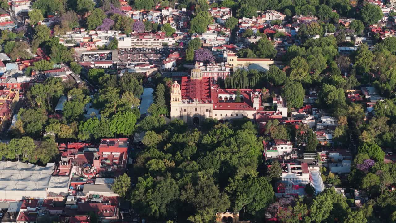 Drone footage of Coyoacan's central area, church framed by dense foliage