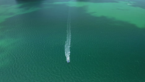 drone tilting down on driving longtail boat on wide ocean scenery, aerial