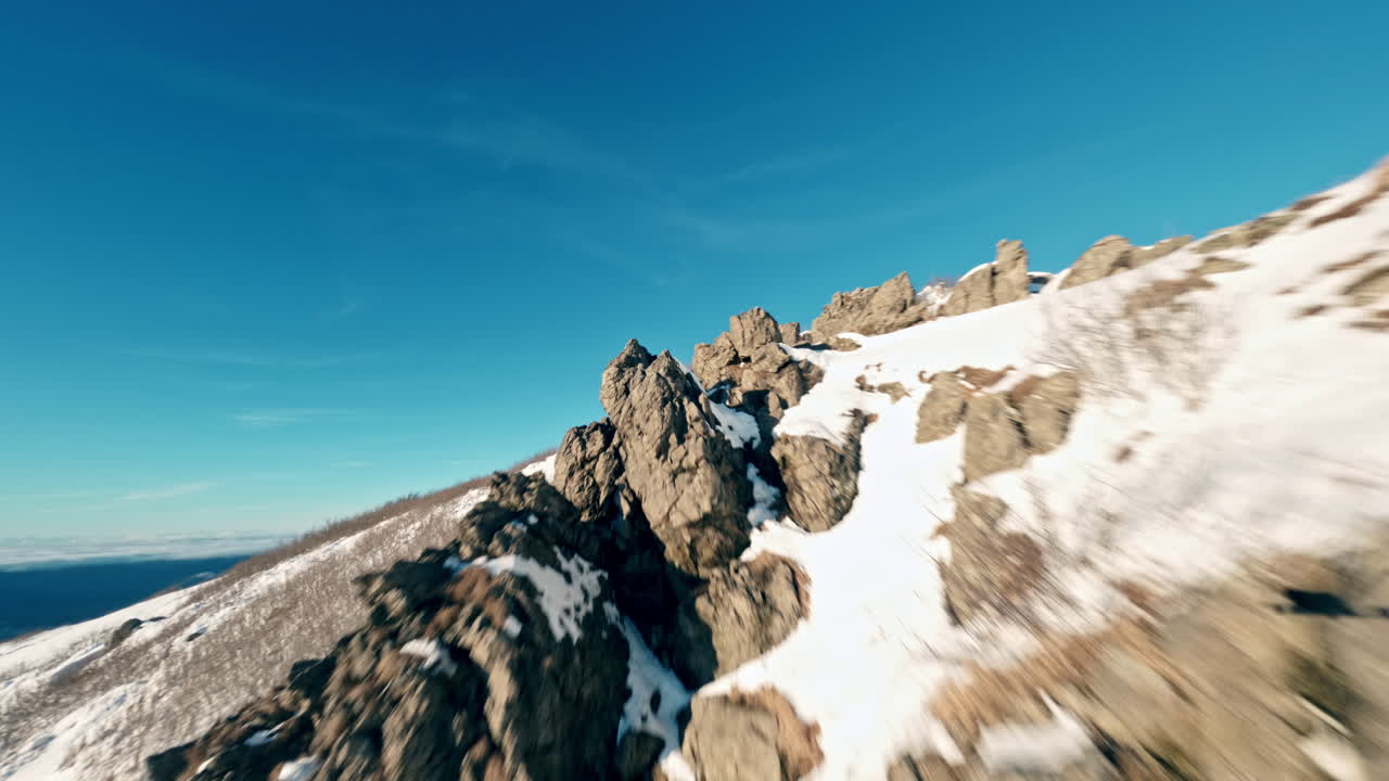 Rocky snow-covered mountain landscape, captured by an FPV drone flying over it