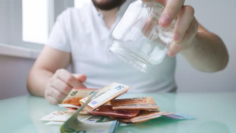 close up of a hands of man taking money out of his glass bank,