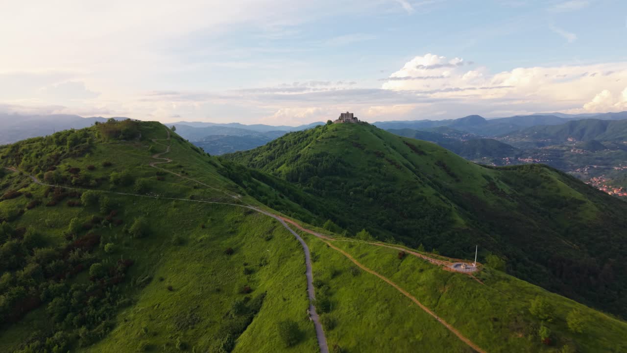Ancient Italian fort on green hills with scenic road and expansive views