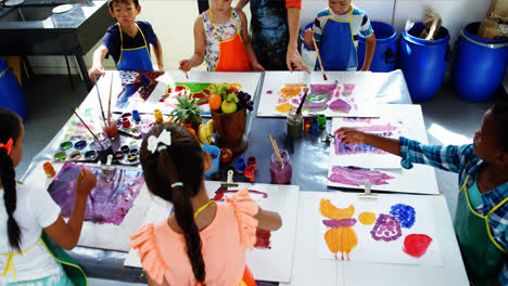 teacher assisting schoolkid in drawing class