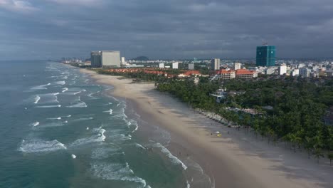 drone flying over famous my khe, my bac an and non nuoc white sand beach with huge waves in danang, central vietnam