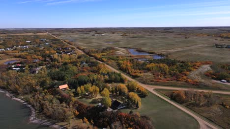 Colorful-autumn-foliage-along-shoreline-of-remote-lake-in-Canadian-prairies