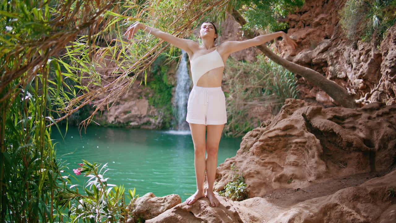 chica meditativa disfrutando del yoga en las rocas naturaleza de la selva soleada mujer levantando las manos