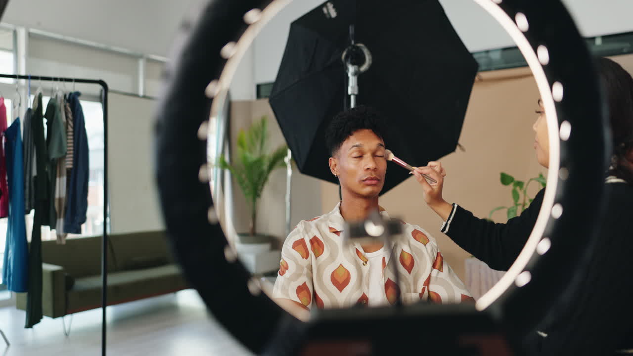 Truccatore che applica il trucco a un uomo in uno studio