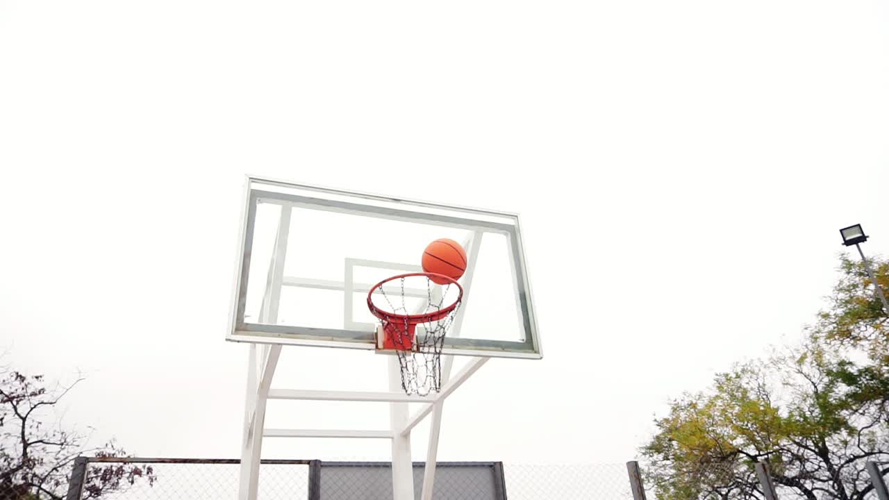 젊은 남자가 공원에서 코트에 농구 공을 성공적으로 던지고, 슬로우 모션  ⁇