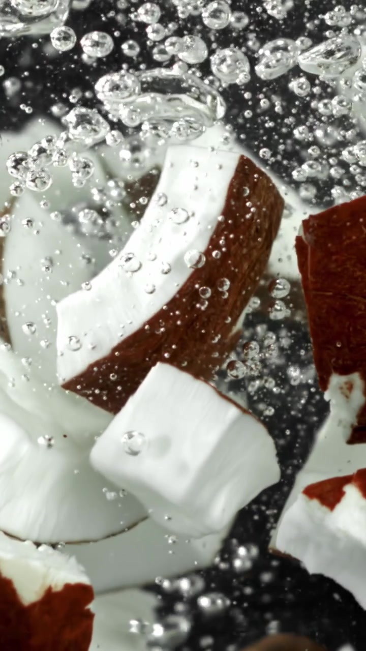 Pezzi di cocco immersi in acqua frizzante su sfondo nero