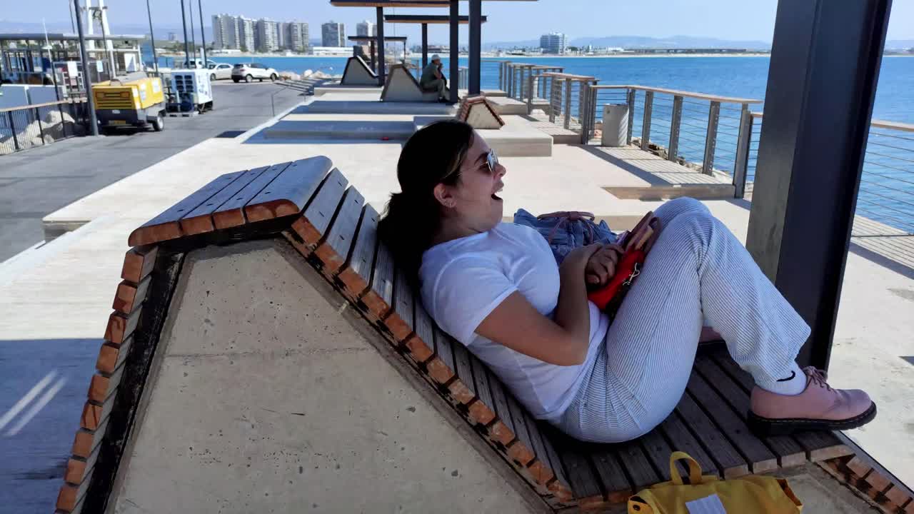Young woman yawning while resting in the port of Akko