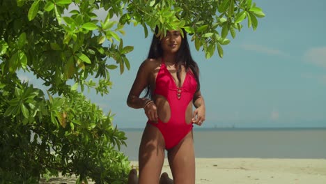 dressed in a red bikini, an indian girl adds charm to a caribbean tropical beach scene kneel in the sand