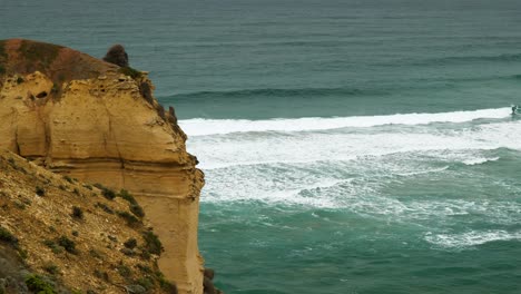 Stunning-video-of-a-powerful-wave-breaking-against-a-vibrant-orange-cliff-on-a-sunny-day