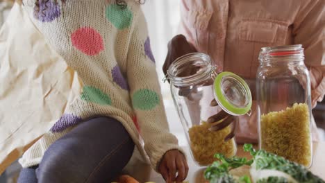 video de una feliz madre y hija afroamericanas desempaquetando comida en la cocina
