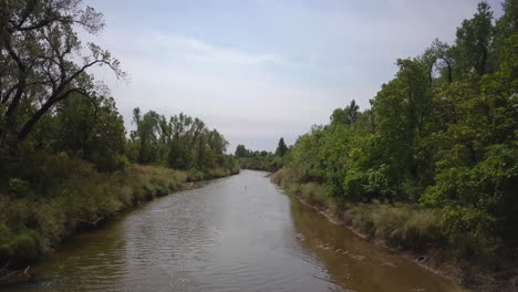 Backwards-dolly-shot-revealing-a-family-kayaking-down-a-small-remote-river