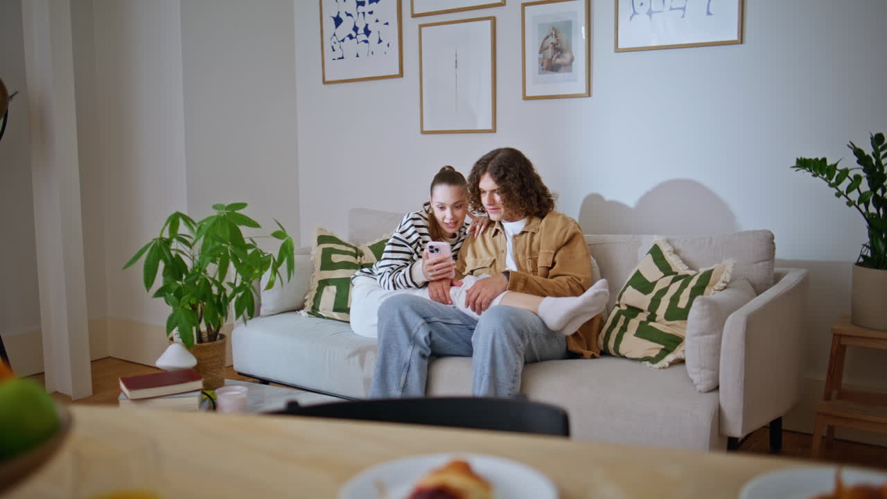 Relaxed couple watching smartphone social media sitting comfortable home couch
