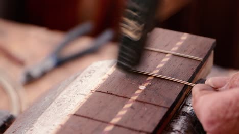 artesano de guitarra inserta trastes en el tablero y los adornos con unos alicates