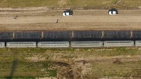 aerial shot of a train moving along tracks in rural argentina, flanked by roads and vehicles