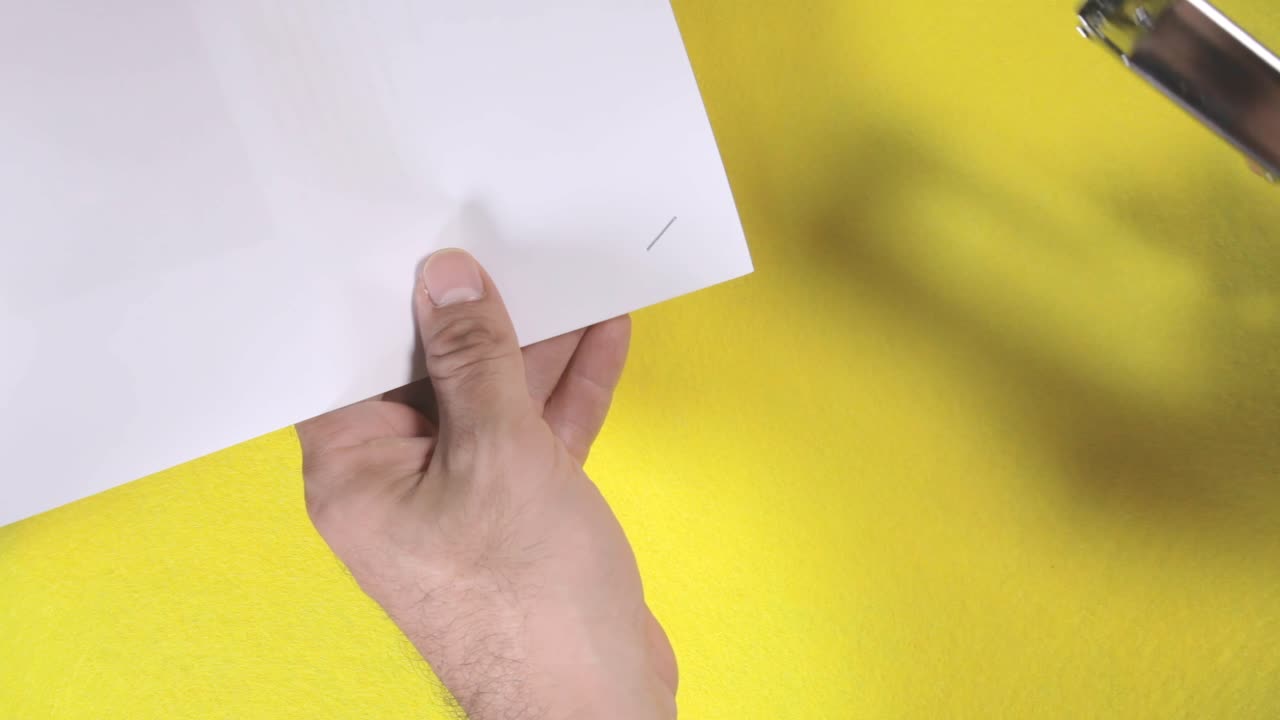 은색 금속 스테이플러는 인쇄된 종이의 컬렉션을 고정시켜 각 모양의 크림프 연결을 형성합니다.