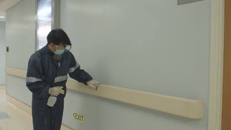 man disinfecting handrails to avoid the spread of coronavirus inside the hospital