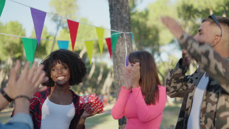 friends celebrating a birthday party outdoors with gift giving and applause
