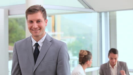 smiling businessman standing in front of his team