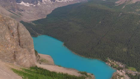 aerial dolly out of emerald lake moraine between pine tree forest and canadian rockies at banff national park, alberta, canada