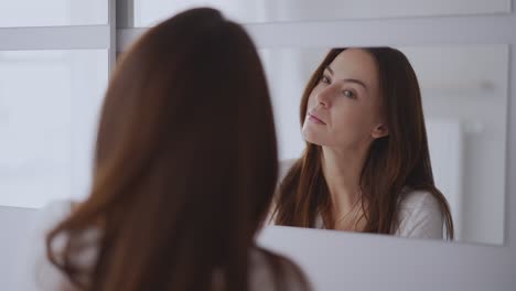 woman applying makeup in front of a mirror