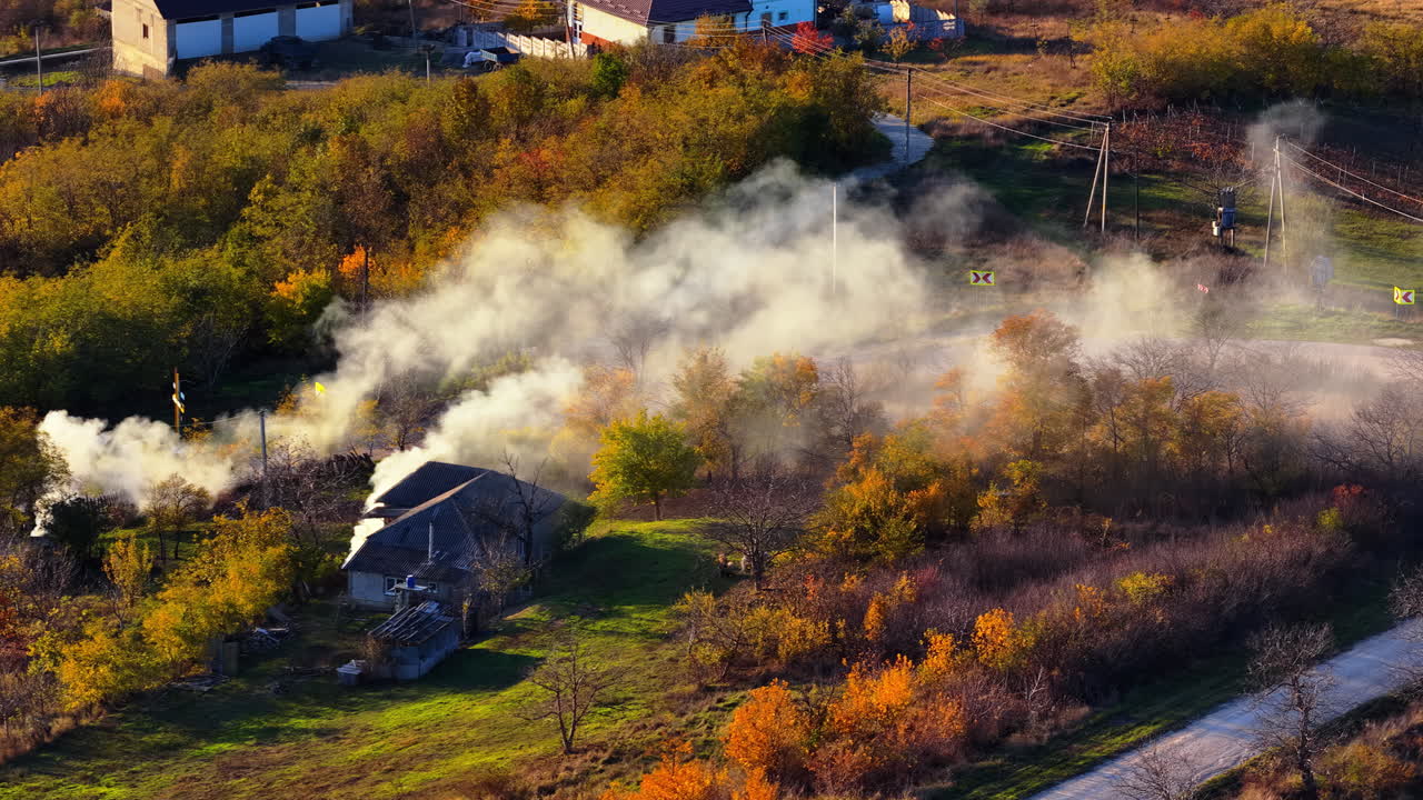 Aerial drone view of smoke rising from farmlands in Moldova at golden hour