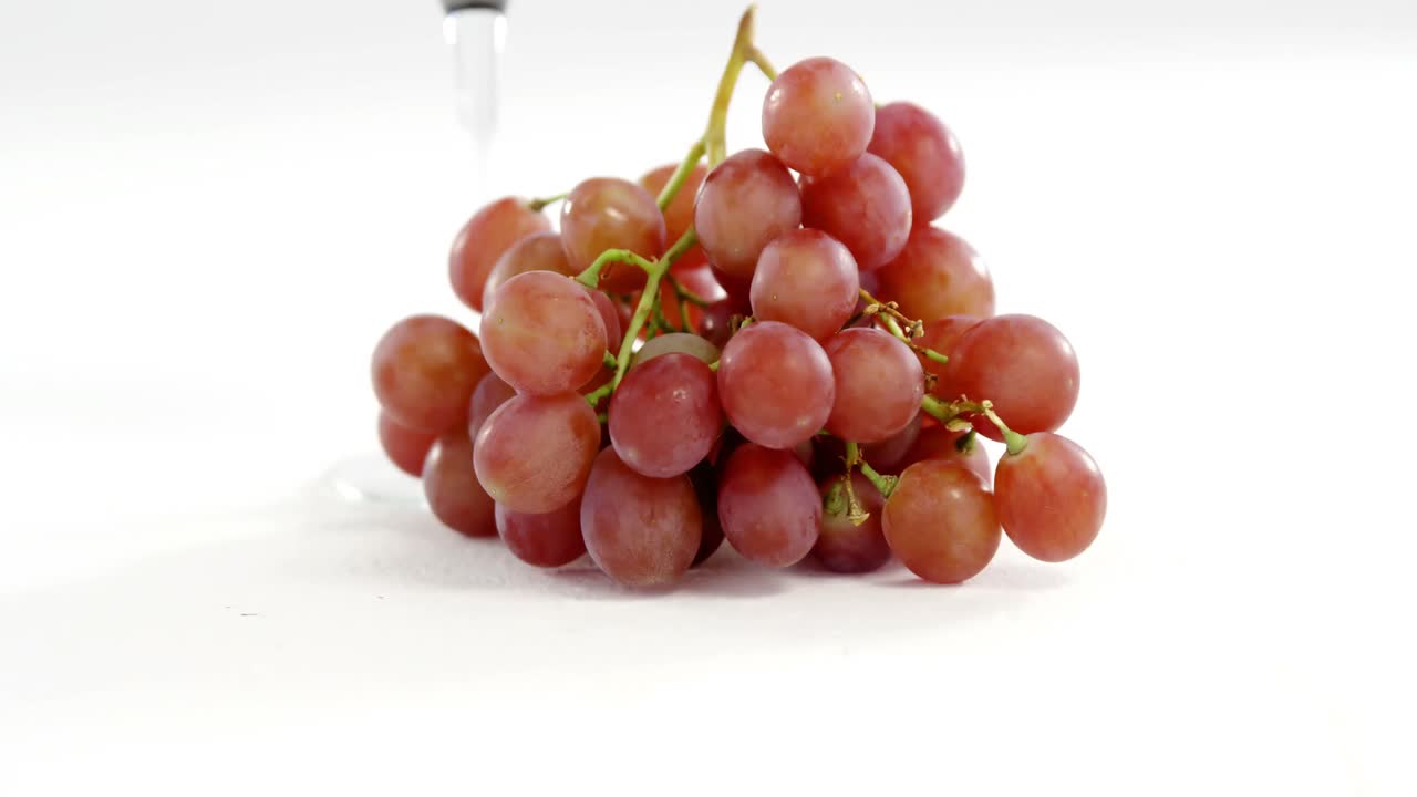 primer plano de un racimo de uvas rojas con un vaso de vino tinto