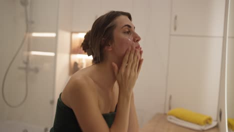 woman applying skincare in bathroom