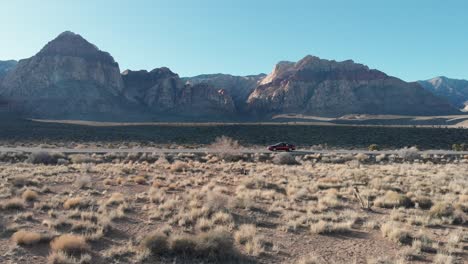 Aerial-drone-shot-of-Red-Rock-Scenic-Highway-with-mountains-in-the-background