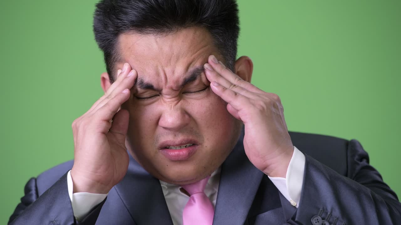 초록색 배경에 젊은 잘생긴 과체중 아시아 사업가