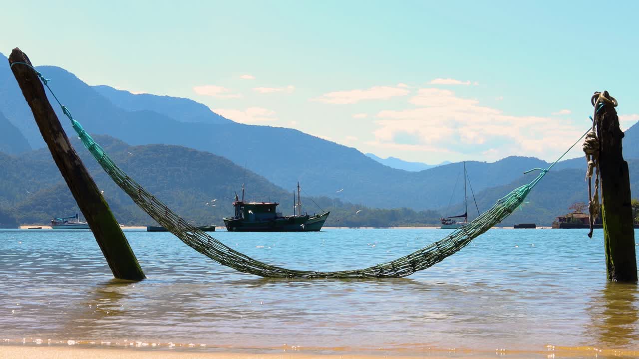 hamaca estática en el agua con fondo marino pacífico con barco de pesca con pájaros volando