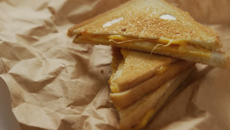 video de primer plano de sándwiches de queso tostado en papel marrón sobre un fondo gris