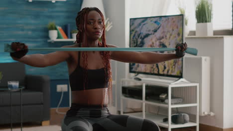 black fit woman doing yoga exercices using yoga bands on fitness ball