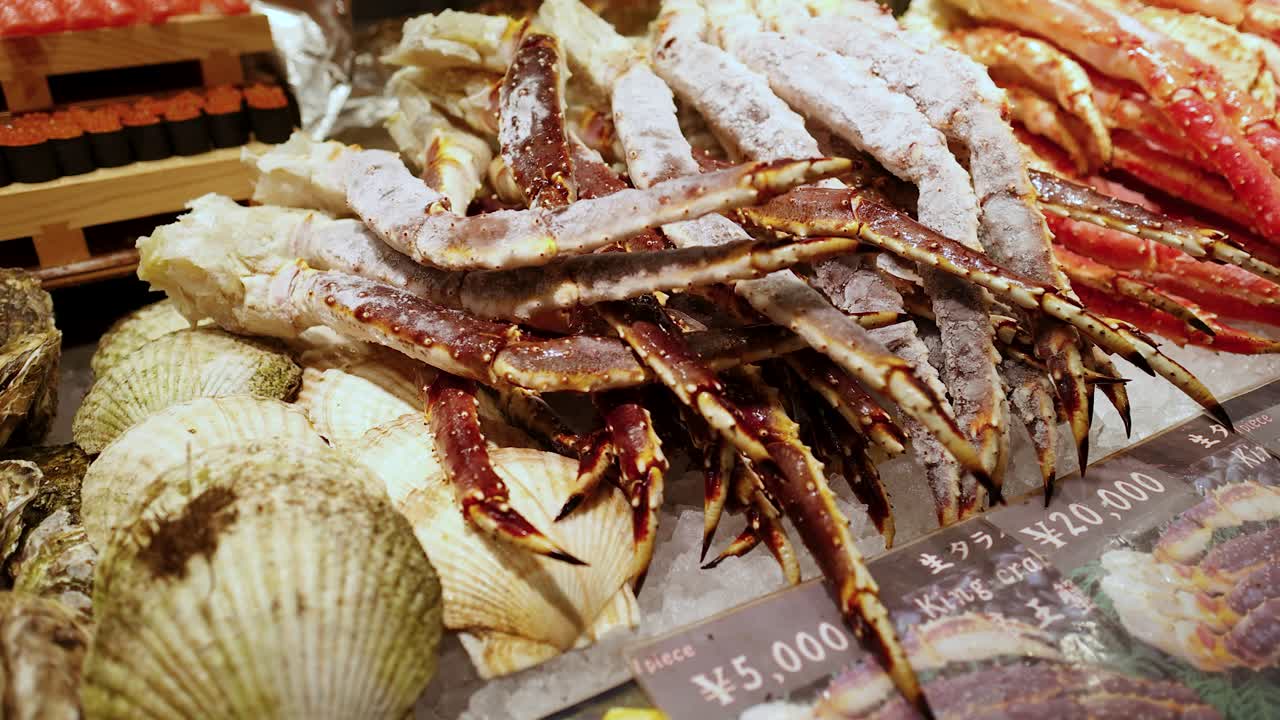 Tomada panorâmica em close-up de patas de caranguejo-real congeladas, ostras e vieiras no gelo no Japão.