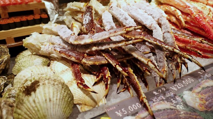 Close-up panning shot of frozen king crab legs, oysters, and scallops on ice in Japan
