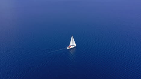 aerial: one sailboat out in the open blue aegean sea on a clear summer day