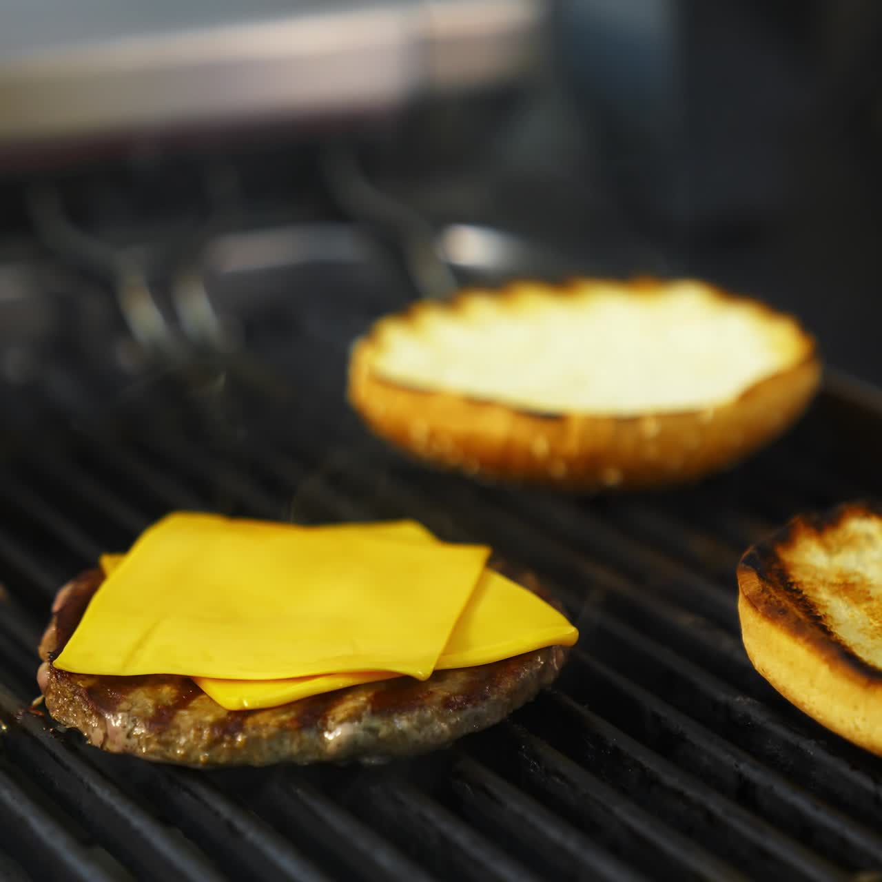 Hands of a person fry buns on grill. Meat cutlet with cheese on top. Fast food concept