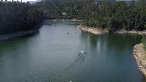 enjoying teleski in the deep quiet ocean surrounded with green tall trees during daytime - aerial shot