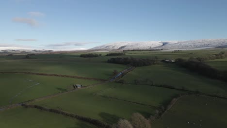 verdant green farmland in lancaster uk, with snow dusted hills beyond