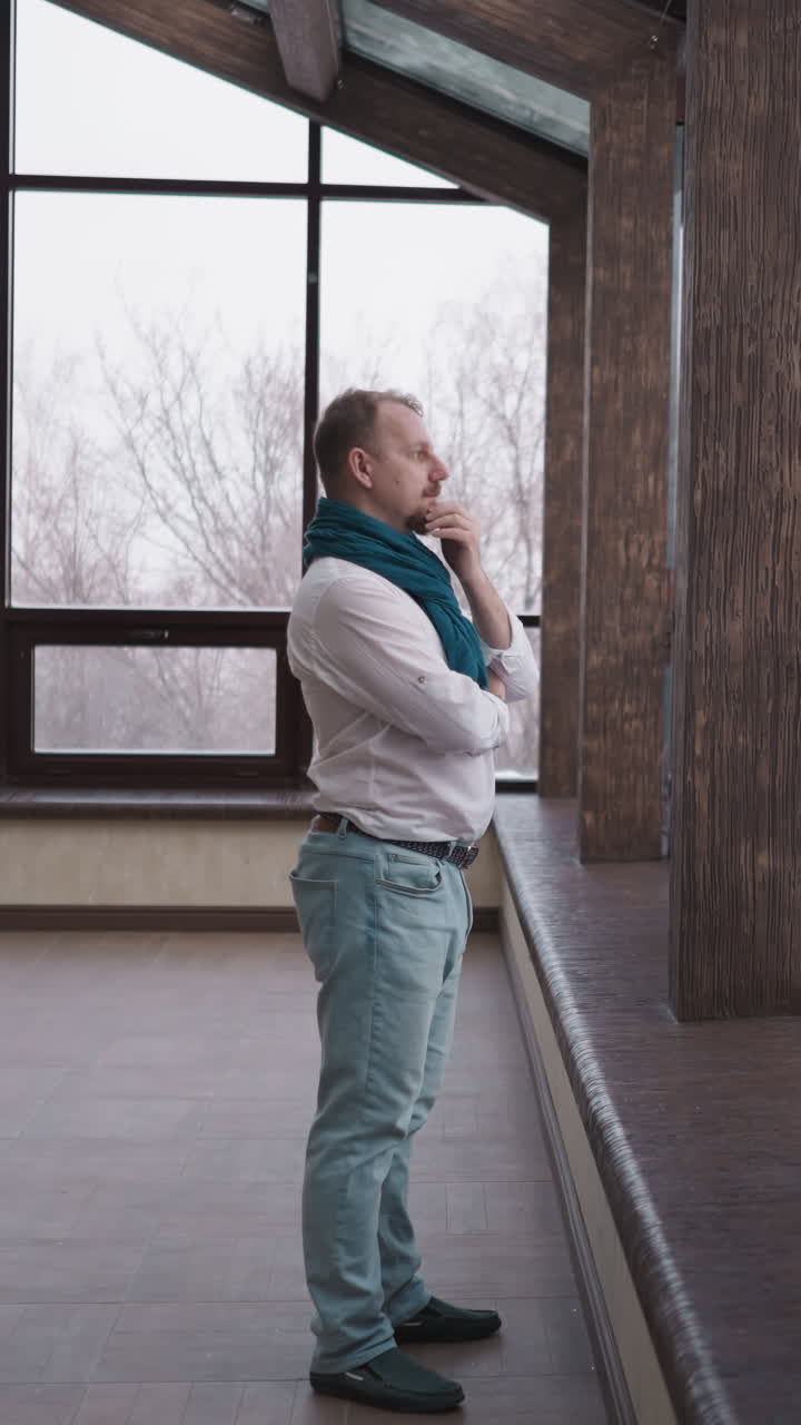 hombre perdido en pensamientos por la ventana panorámica. hombre maduro reflectante en pañuelo se encuentra en reposo solitario cerca de las ventanas de la terraza absorbido en reflexiones contemplativas