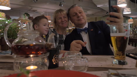 grandparents and grandson making selfie during family dinner in restaurant