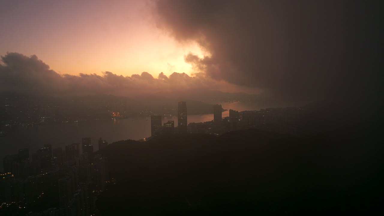 Dreamy drone lifting shots into slowly moving cumulus clouds during a colorful sunrise with a great view on Tai Koo and Quarry Bay in Hong Kong.