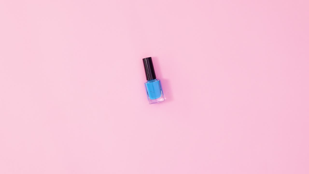 Manicure neglelakflaske roterende på pastelrosa baggrund. Stop motion flat lay
